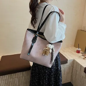 Pink embossed retro tote bag with black straps and a cute plush bear charm for women