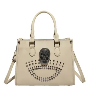 Beige faux leather handbag with black rhinestone skull and dark metal rivets