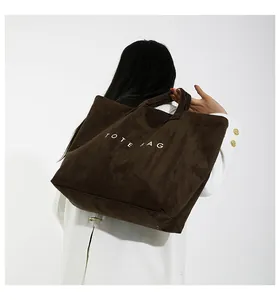 Dettaglio della borsa tote in velluto a coste marrone scuro con scritta bianca TOTE BAG