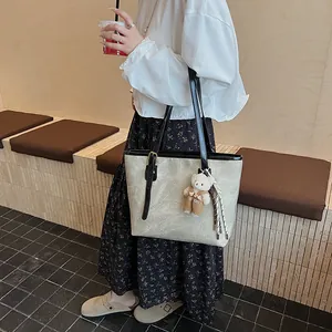 Retro cream tote bag with floral embossing, black shoulder straps and teddy bear charm