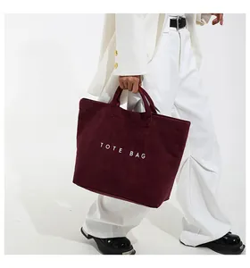 Dettaglio della borsa tote in velluto a coste bordeaux con trama e logo stampato