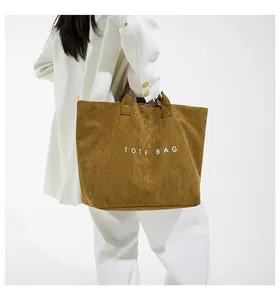 Vista posteriore di una modella con una borsa tote grande in velluto a coste marrone