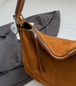 Detalle de cremallera metálica y textura de ante marrón en bolso tote grande
