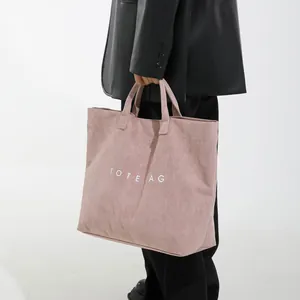 Grande borsa shopper rosa in velluto a coste con scritta bianca mostrata da modella