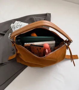 Vista macro del interior espacioso de un bolso de ante con portátil y accesorios