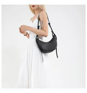 Détail du sac croissant noir avec texture litchi et lettrage doré sur un mannequin