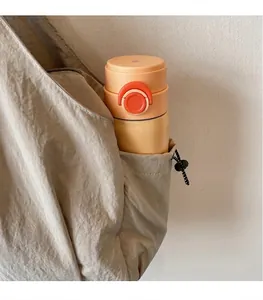 Detail of yellow portable thermos cup with carrying loop inside a beige canvas tote bag