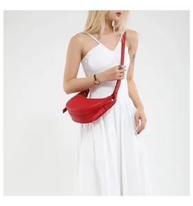 Détail du sac demi-lune rouge en cuir grainé porté sur une robe d'été blanche