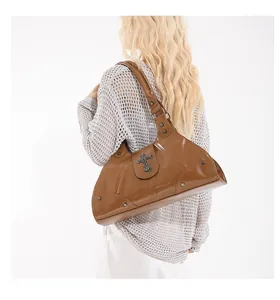 Close-up of caramel brown patent leather shoulder bag with punk cross and rivet details