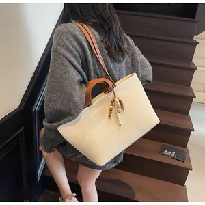 Detail of canvas tote bag with brown leather straps and beaded charm on wooden stairs
