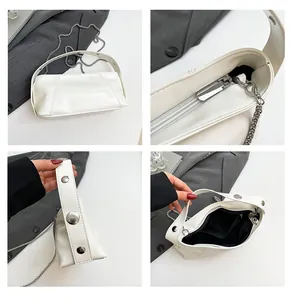 Detail view of white glossy handbag featuring silver studs and chain strap highlights