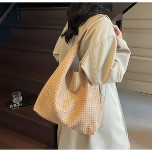 Detailed view of brown woven tote bag on shoulder showcasing large capacity and leather texture