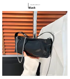 Detail of black glossy shoulder bag with elegant silver chain and wide strap