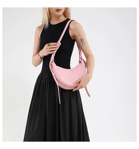 Sac demi-lune rose en cuir grainé porté par un mannequin avec bandoulière ajustable