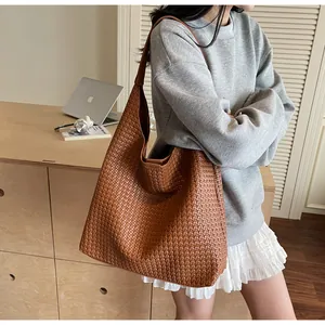 Close-up of caramel brown woven leather texture on a spacious hobo tote shoulder bag