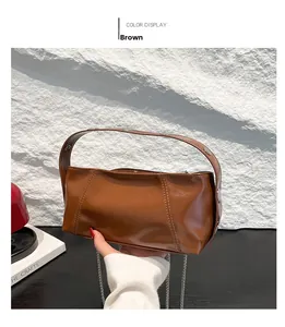 Detail view of the brown synthetic leather bag with symmetrical stitching and metal buckles