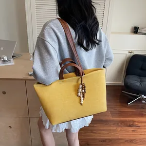 Large yellow canvas tote bag with brown leather straps and colorful beaded charm