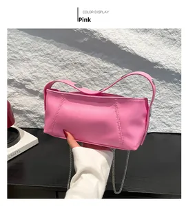 Close-up of pink glossy cylinder bag with silver chain strap and metal rivet details
