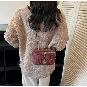 Détail d'un sac matelassé bordeaux avec strass et pendentif en forme de rose dorée