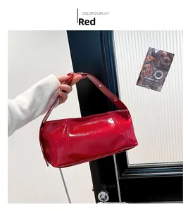 Detail of red glossy leather cylinder bag with wide strap and chic metal chain accessory