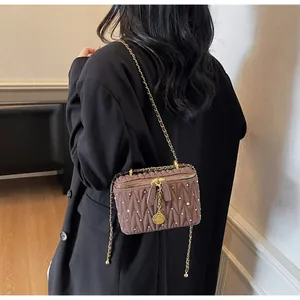 Détail du sac boîte marron matelassé avec strass et pendentif rose élégant