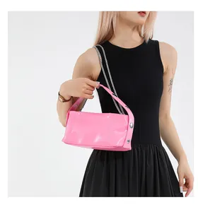Pink patent leather shoulder bag with silver chain and rivet details on model
