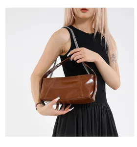 Detail of glossy brown underarm bag with silver chain strap and metallic texture