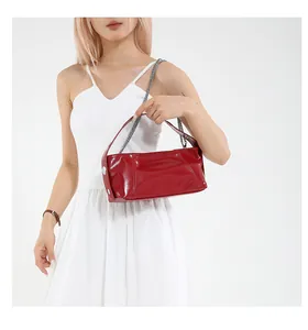 Detail of red patent leather cylinder bag with silver metal buckle and chain strap