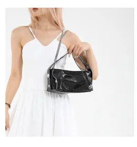 Detail view of glossy black faux leather shoulder bag with chic silver metal buckles