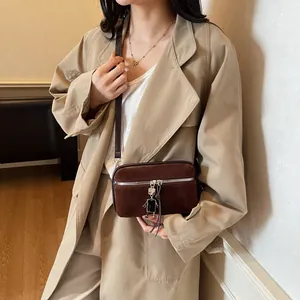 Minimalist dark brown suede crossbody square bag with cute robot metal charm on model