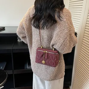 Mini sac bordeaux matelassé avec strass, chaîne dorée et breloque fleurie sur modèle