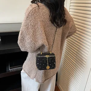 Sac boîte matelassé noir avec cristaux blancs et pendentif camélia doré sur bandoulière