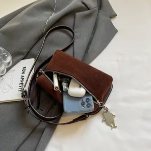 Dark brown matte crossbody bag with adjustable strap and interior essentials display