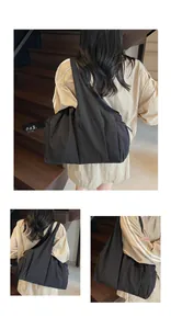 Macro view of matte black nylon tote bag featuring drawstring closure and wide shoulder strap