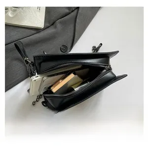 Detail view of black faux leather crossbody bag showing interior storage capacity with phone