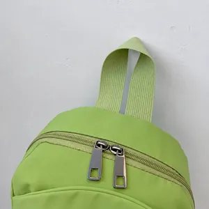 Detail van lichtgroene nylon rugzak met stevige handgreep en metalen ritsluitingen