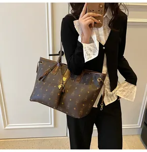 Detail of large tote bag in dark brown with monogram print and small accessory pouch