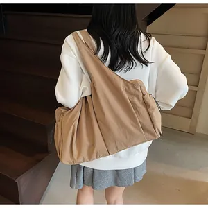 Rear view of khaki large capacity nylon crossbody bag worn on a casual shoulder