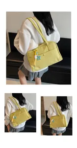 Détail du sac bandoulière en toile jaune vif avec breloque étoile et poche frontale