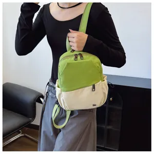Detalle de mini mochila de nailon bicolor verde y beige mostrada en una modelo