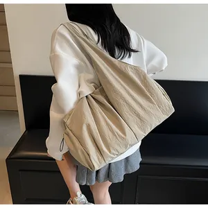 Detail of khaki pleated canvas tote bag showing large capacity and textured fabric on model
