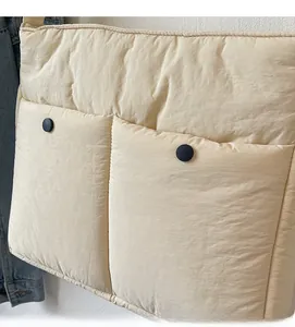 Detail of beige quilted shoulder bag featuring two front pockets with black buttons