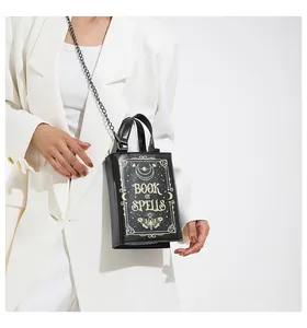 Close-up of gothic Book of Spells handbag with gold moon and moth patterns on white suit