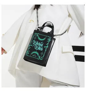 Detail of a book-shaped Wicked Witch handbag with mint green text and metal chain strap