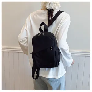 Vue détaillée du sac à dos en nylon noir montrant la poche latérale et le logo DD