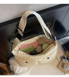 Macro shot of spacious inner compartment of cream puffer crossbody bag holding daily items