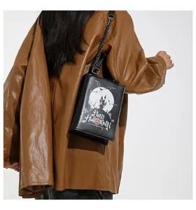Detail of Halloween pumpkin crossbody bag featuring a black metal chain strap and leather handle