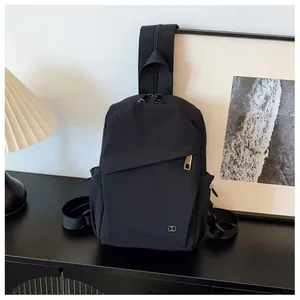 Detalle del bolso bandolera de nailon negro con cremallera asimétrica y logotipo metálico DD