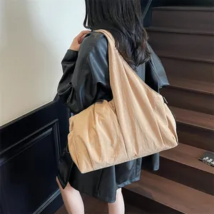 Large khaki pleated canvas tote bag worn by model on stairs, stylish daily commuter handbag