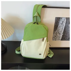 Vue détaillée d'un sac bandoulière en nylon vert et beige sur une table minimaliste